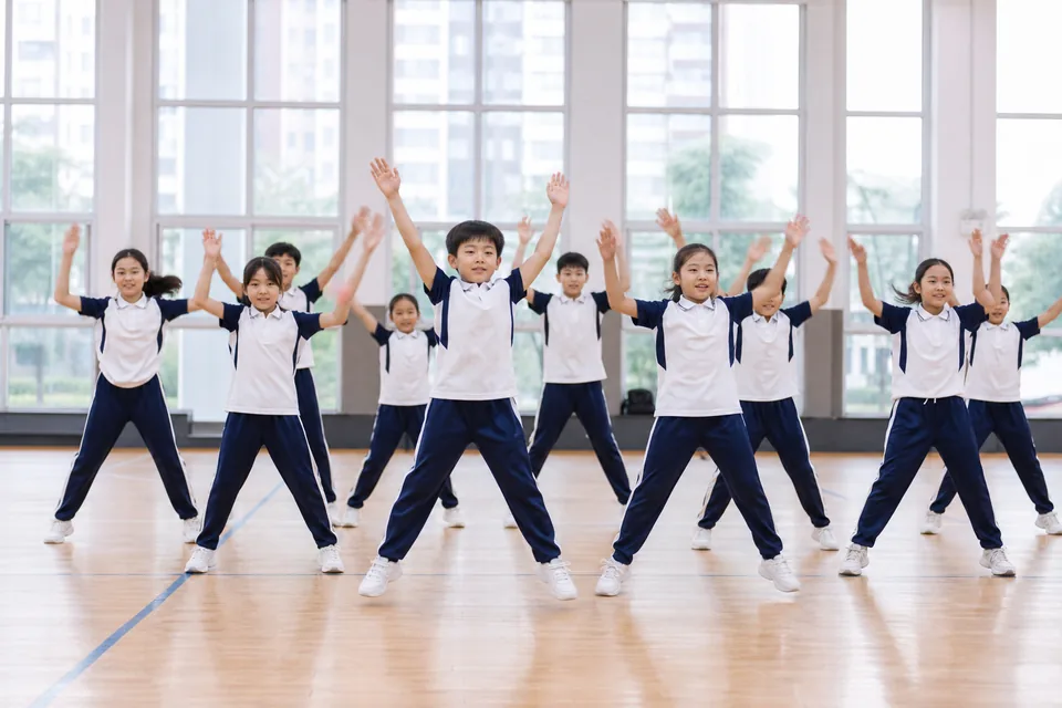 约十名学生在体育馆同步进行开合跳练习
